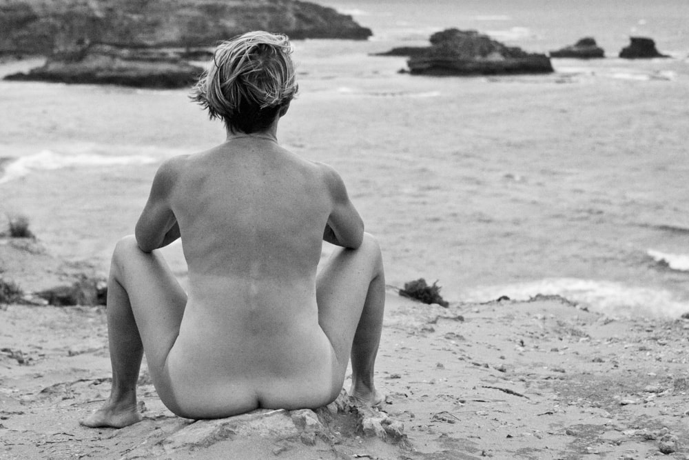 nude woman sitting on beach
