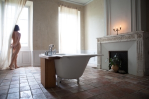 woman in beautiful bathroom, looking out the window.