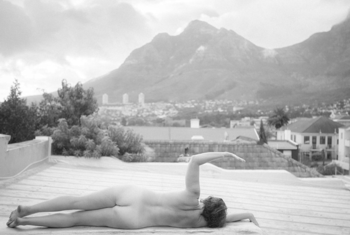 nude woman laying on deck overlooking mountains